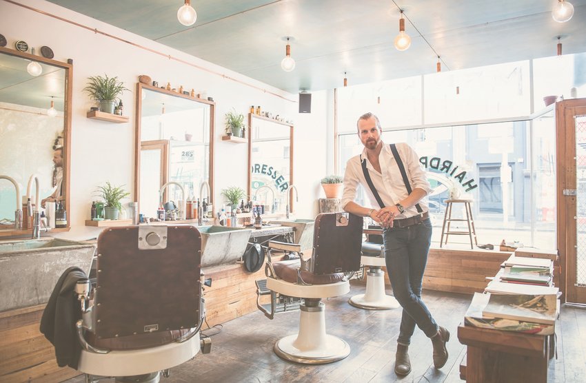 Coiffeur-visagiste souriant dans son salon de coiffure